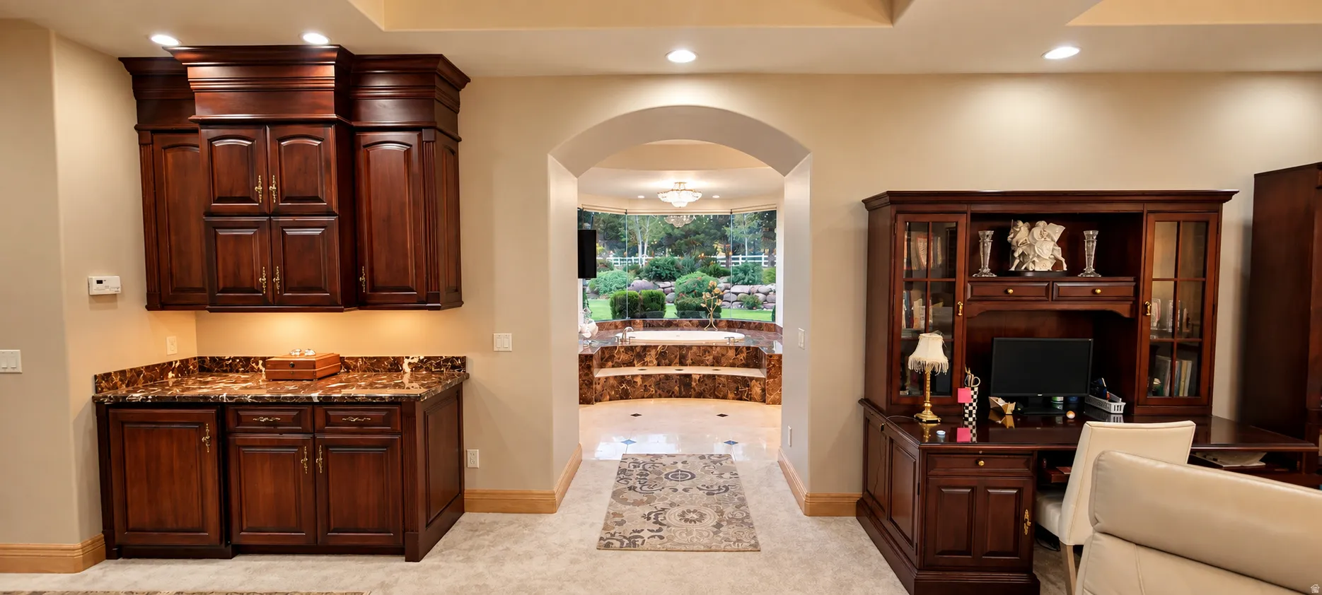 Built-in cabinetry with stone-finish countertop, recessed lighting, arched doorway, and built-in desk unit