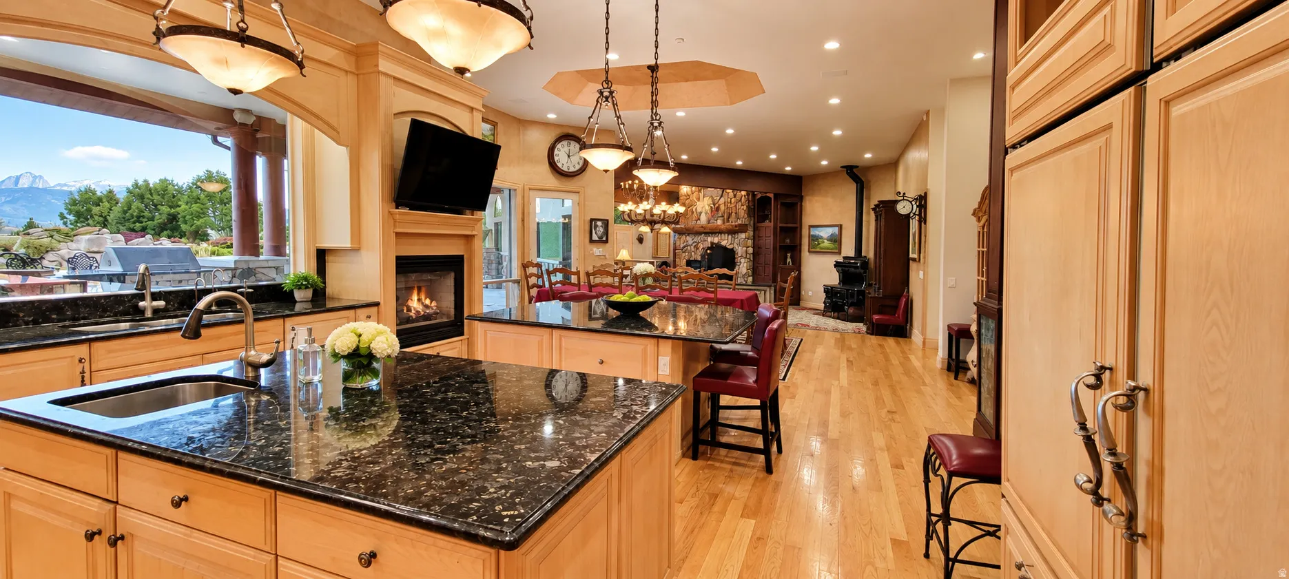 Kitchen featuring dual islands with dark stone countertops, light wood cabinetry, and a built-in sink