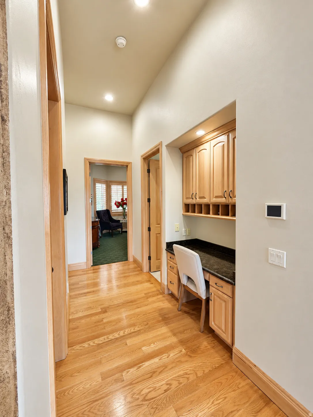 Hallway featuring wood-finish flooring, recessed lighting, built-in desk with stone countertop, and custom cabinetry