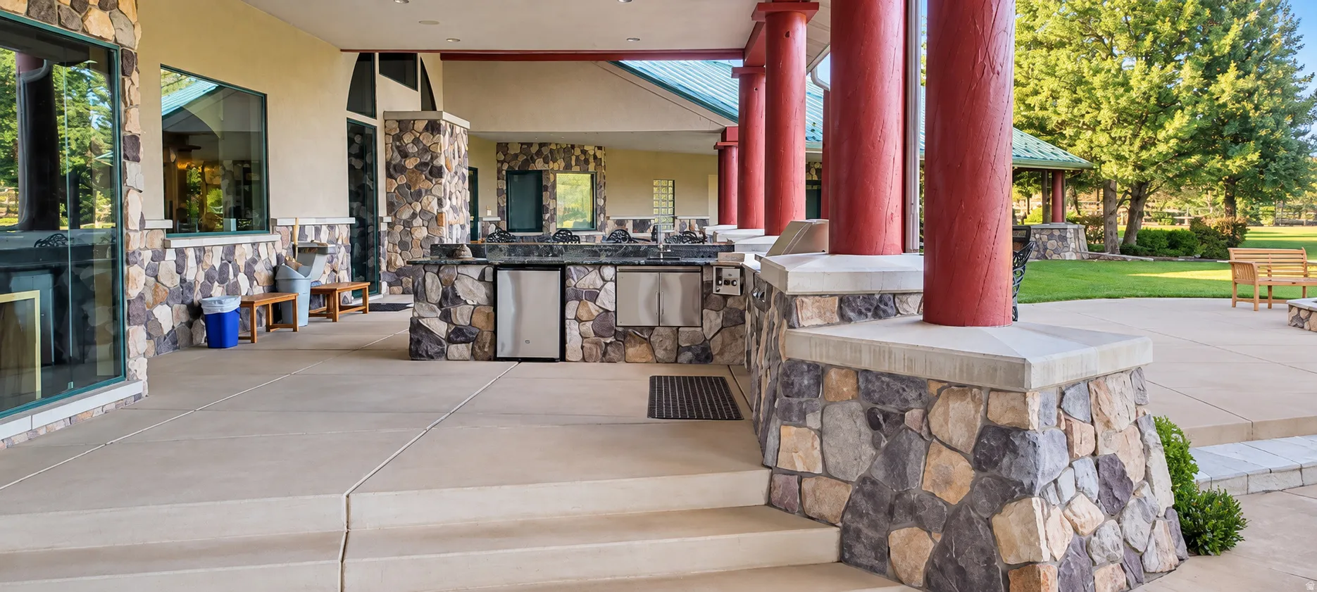 Outdoor entertaining area with a built-in stone island, integrated grill, and under-counter refrigerators