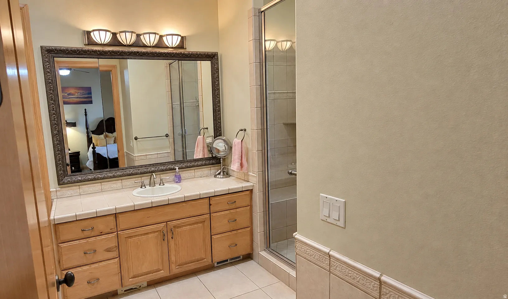 Wood-finish vanity with ample storage drawers and cabinets, complemented by a tiled countertop with an integrated sink