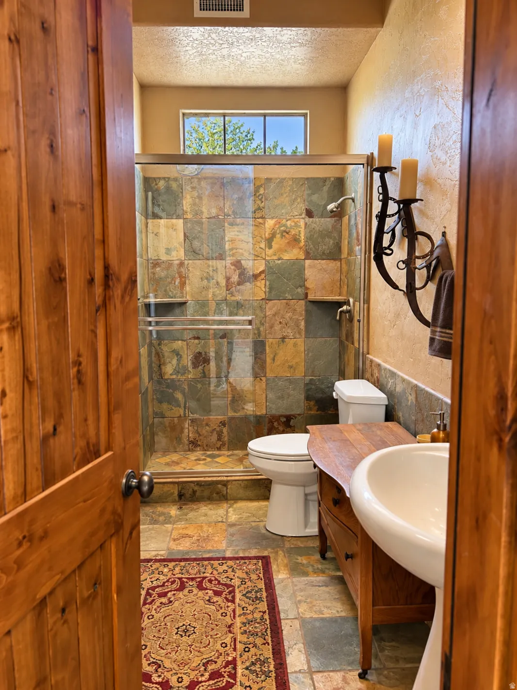 Walk-in shower with natural stone tile surround and glass enclosure