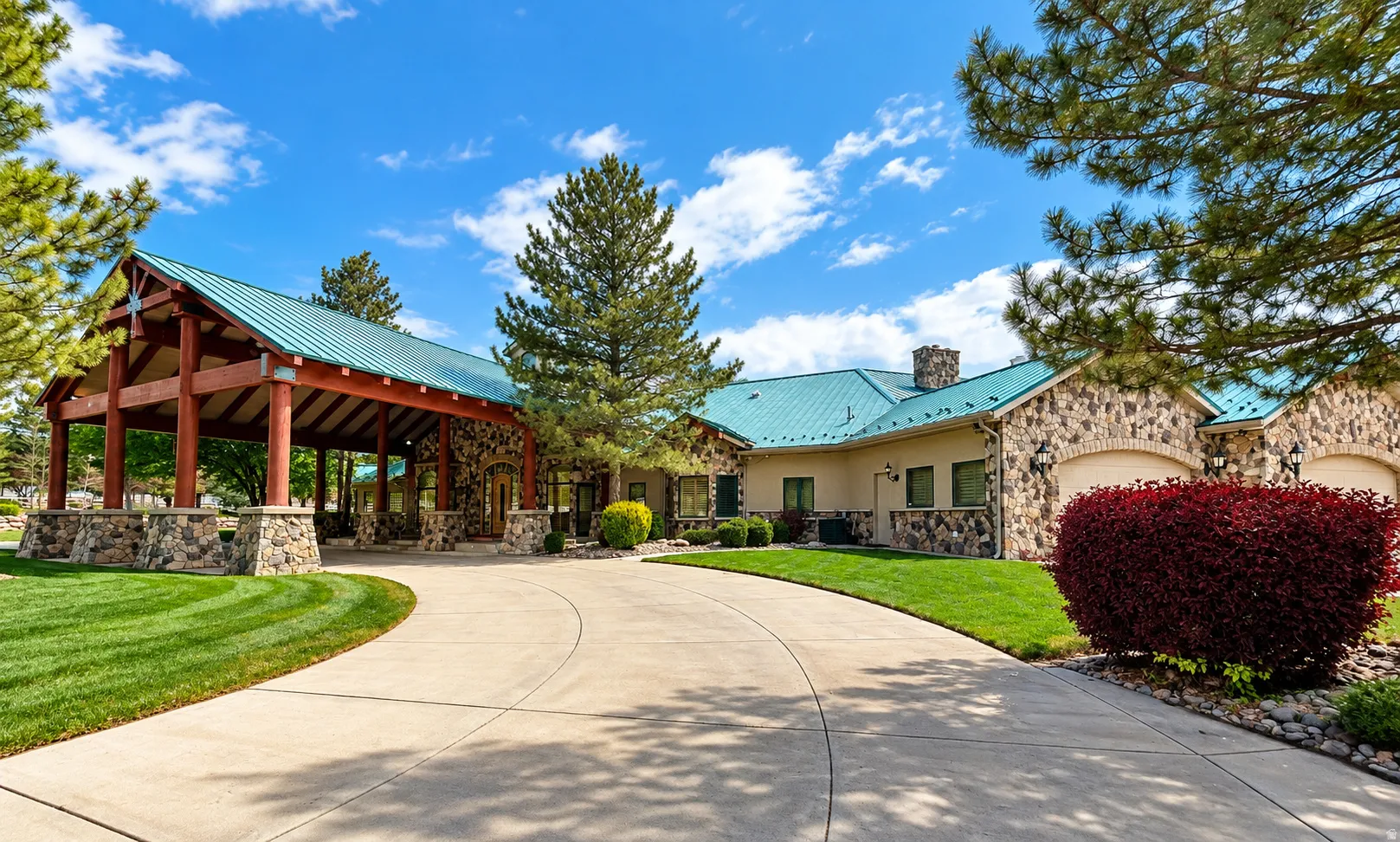 Stone exterior with a covered entry, arched garage doors, and a teal metal roof