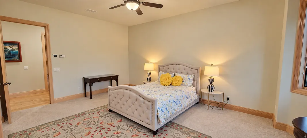 Carpeted room with a ceiling fan, light-colored walls, and wood trim around the doorway