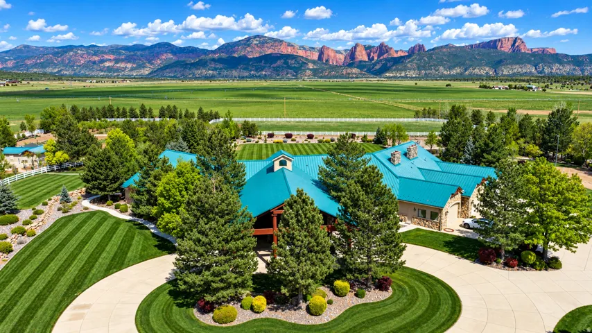 Expansive green metal roof, stone exterior detailing, and a circular driveway