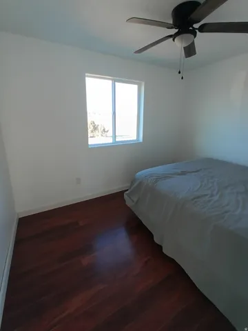 Bedroom with dark wood-style flooring and ceiling fan