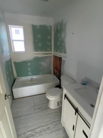 Full bathroom with vanity, a tub, and light marble finish flooring