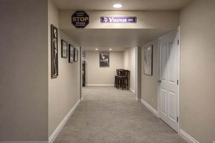 Carpeted hallway featuring recessed lighting, a paneled interior door, and light-toned wall finishes