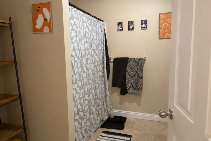 Bathroom featuring a shower with shower curtain and baseboards