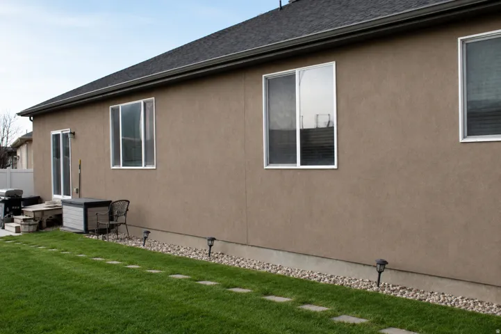 Rear exterior featuring stucco siding and multiple windows. AI Adjusted Photo