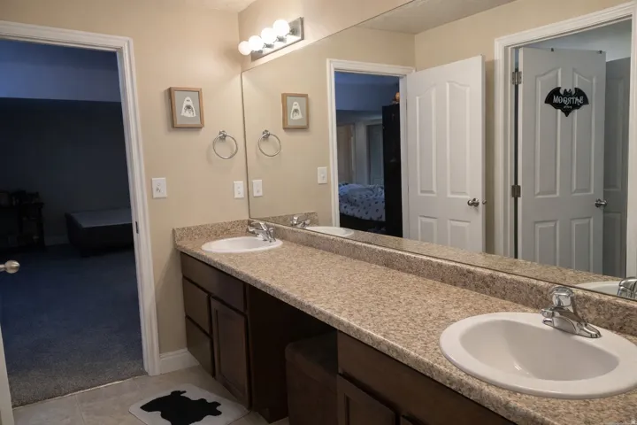Bathroom with light colored carpet, double vanity, ensuite bathroom, and light tile patterned floors