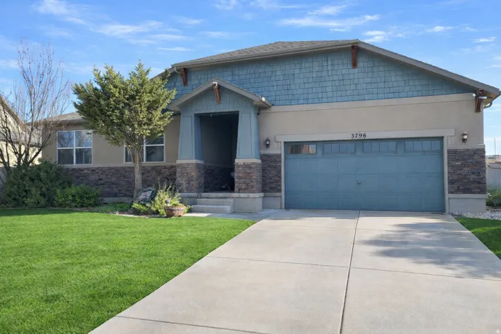 Craftsman-style house with stone siding, stucco siding, a front yard, and a garage