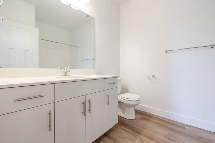 Bathroom featuring a light-toned vanity with a single sink, light stone-finish countertop, and stainless steel hardware