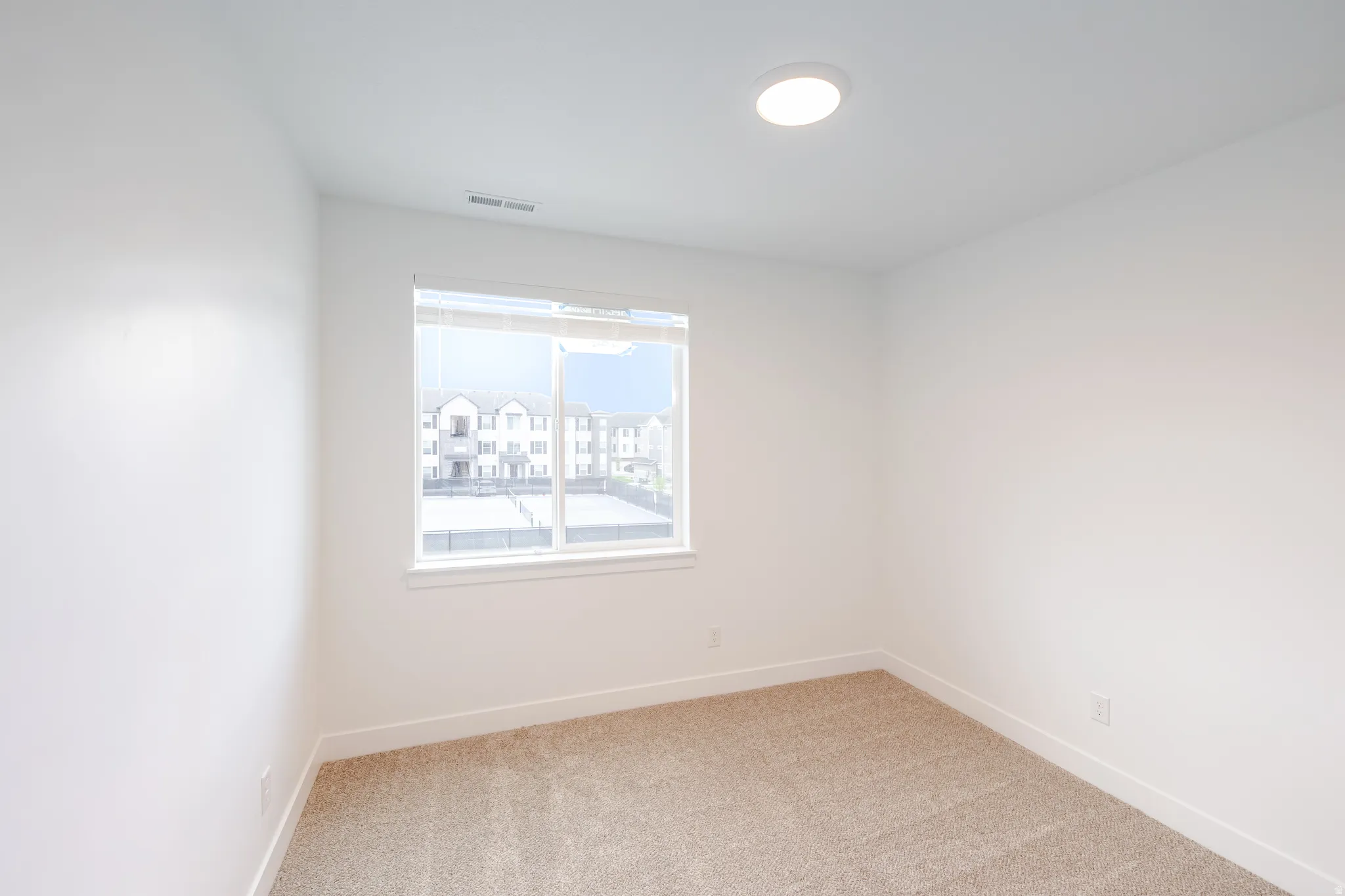 Carpeted room featuring a single window, recessed lighting, and white baseboards