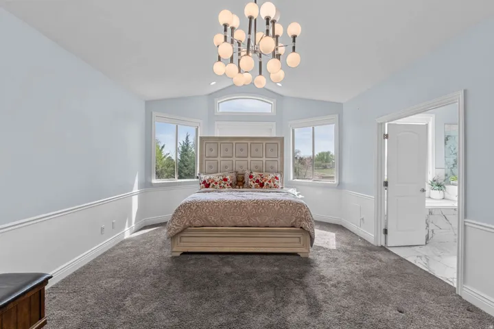 Bedroom featuring carpet floors, vaulted ceiling, and a chandelier