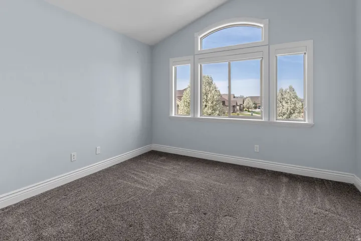 Spare room with dark carpet and lofted ceiling