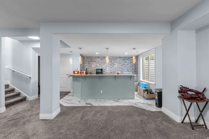 Bar featuring carpet flooring, hanging light fixtures, and an accent wall