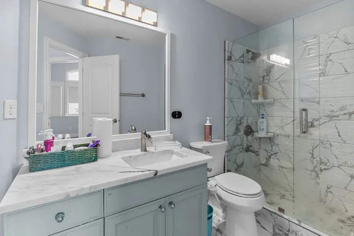 Bathroom featuring vanity, a marble finish shower, and marble finish floors