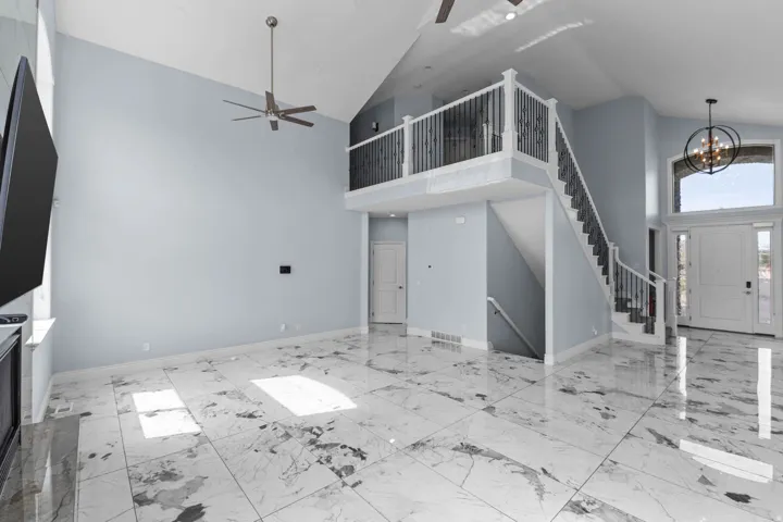 Unfurnished living room with lofted ceiling, a ceiling fan, and hanging lights