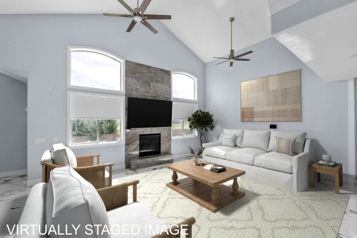 Living area featuring marble finish flooring, vaulted ceiling, a ceiling fan, and a fireplace