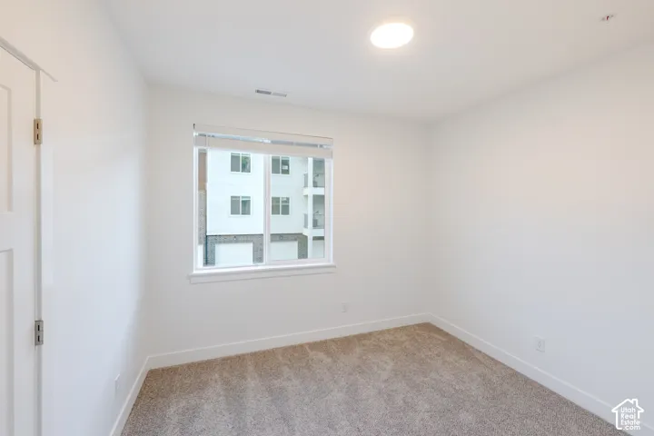 Neutral-toned carpeting, crisp white walls, flush-mount ceiling lighting, and a single-pane window featuring installed blinds