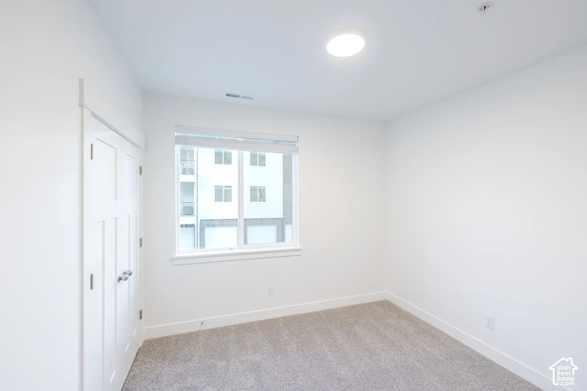 Neutral-toned interior space featuring wall-to-wall carpeting, white interior paint, recessed ceiling lighting, and a double-panel closet door