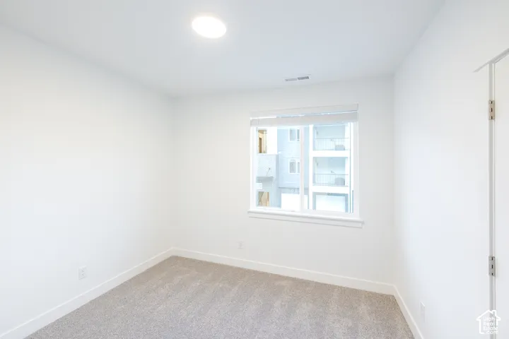 Neutral-toned carpeting, crisp white wall finishes, energy-efficient flush-mount lighting, and a single-pane window with custom blinds