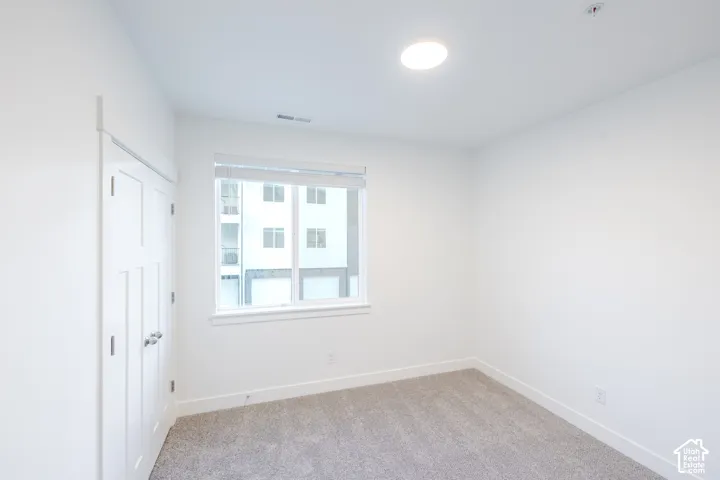 Neutral-toned interior space featuring wall-to-wall carpeting, white interior paint, recessed ceiling lighting, and a double-panel closet door