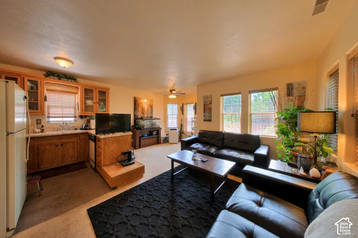ADU Living area featuring light carpet, ceiling fan and many windows, bringing the outdoors in.