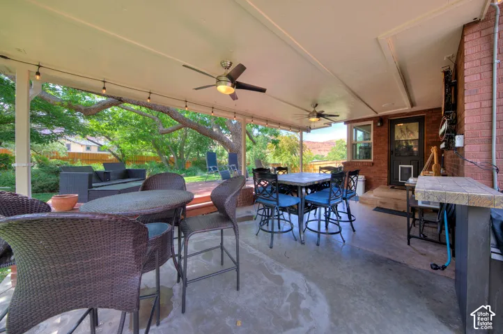 View of Covered patio / terrace featuring outdoor dining area and 2 ceiling fans  - Bluetooth speakers and party lights round out this fun space