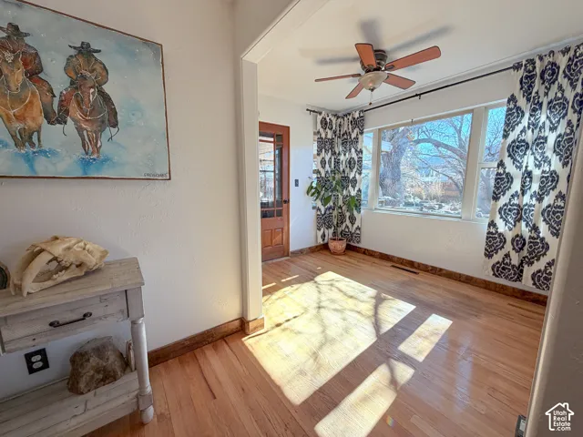 Sunroom with wood floors and a ceiling fan leads out to the covered patio area