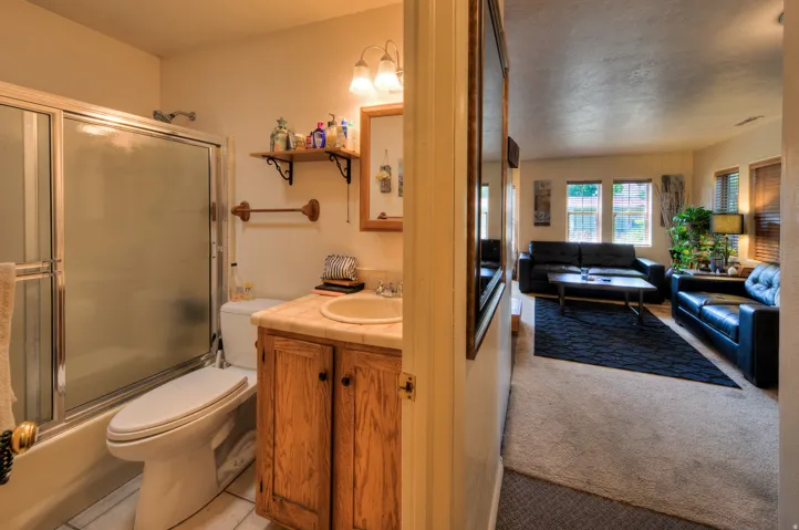 Apartment bathroom featuring vanity, enclosed tub / shower combo, light colored carpet, and a textured ceiling