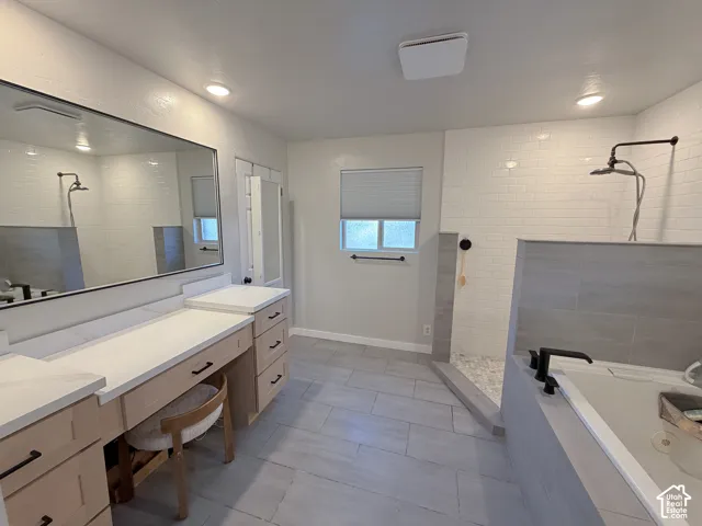 Main floor Spa Bathroom featuring a walk in shower, a garden tub, vanity, and light tile patterned floors
