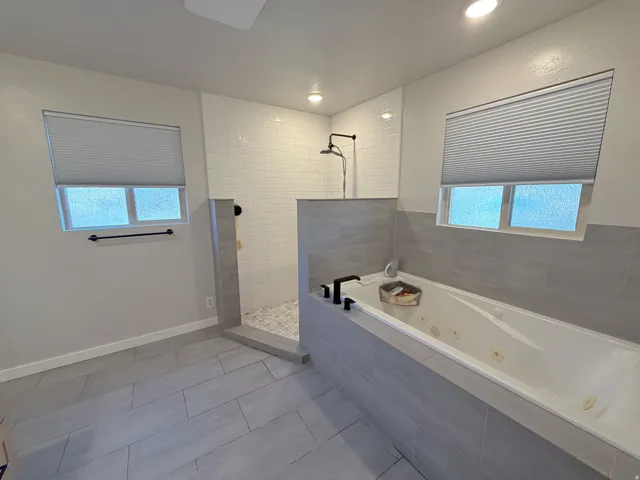 Bathroom with walk in shower, a jetted tub, plenty of natural light, tile patterned flooring, and recessed lighting