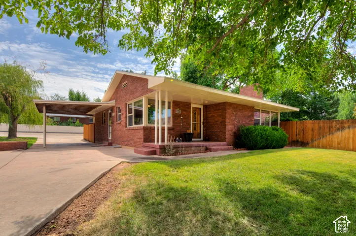 View of front of home featuring an attached carport, circular driveway, brick siding and front porch