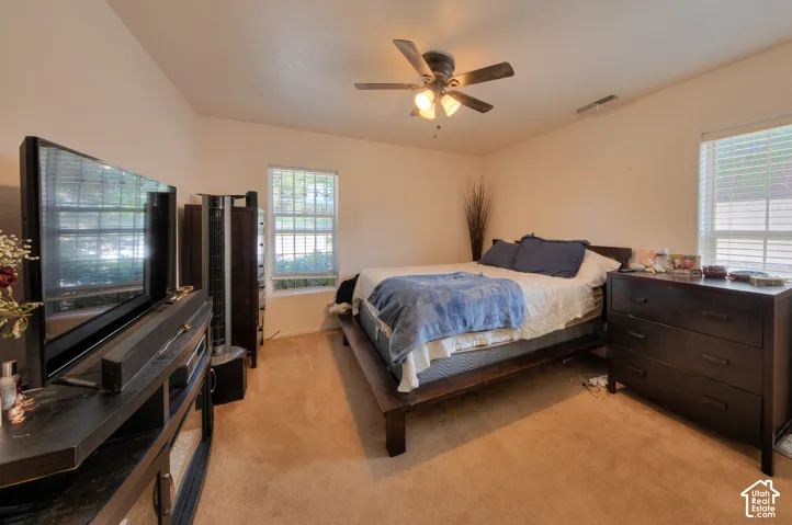 ADU generous size bedroom featuring light colored carpet, bountiful windows, large closet space & ceiling fan