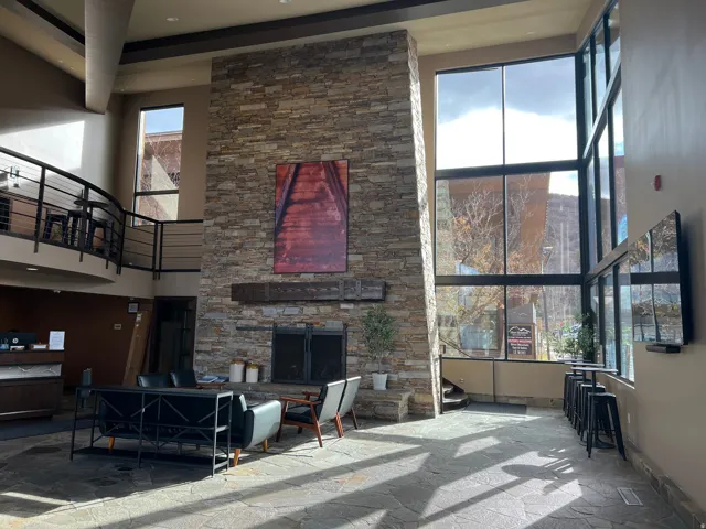 Living room featuring a high ceiling, stone finish flooring, an outdoor stone fireplace, and recessed lighting
