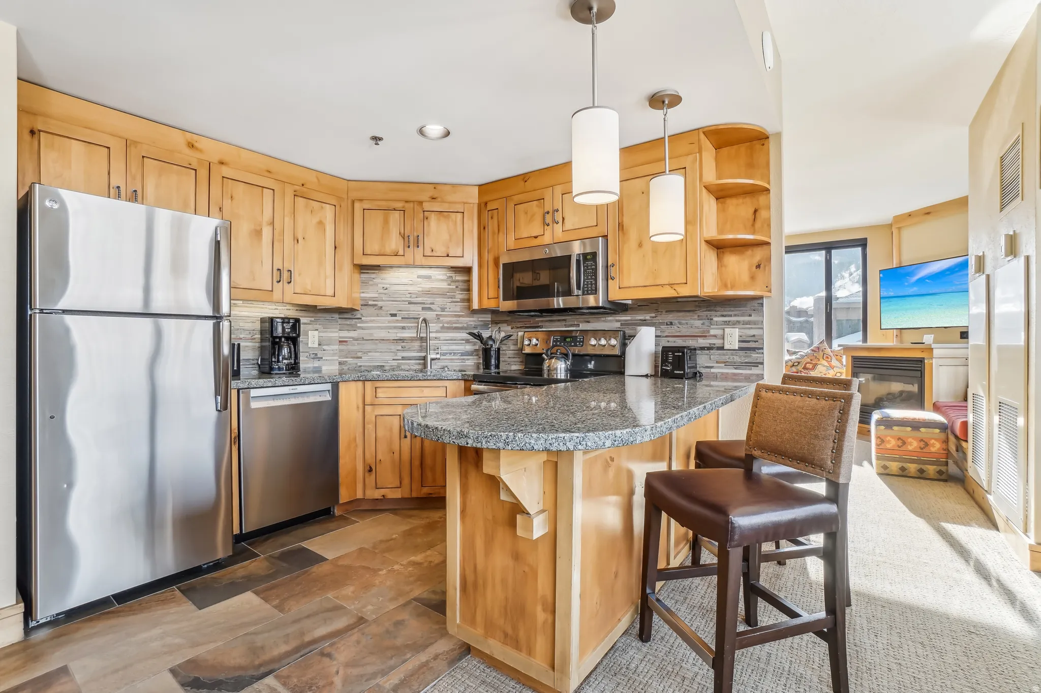 Kitchen featuring stainless steel appliances, a kitchen breakfast bar, decorative light fixtures, a peninsula, and decorative backsplash