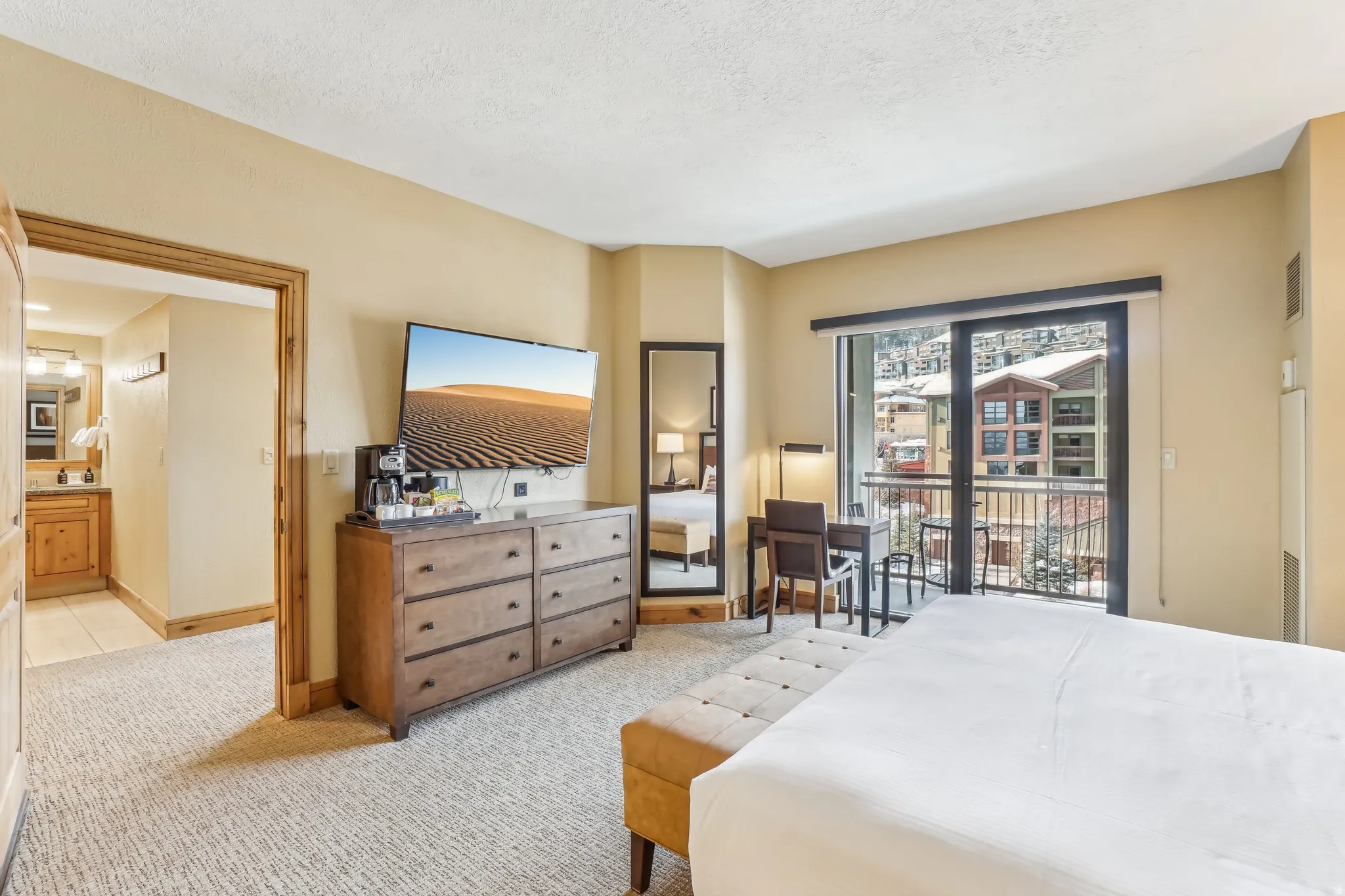 Bedroom featuring light colored carpet, access to exterior, ensuite bath, and a textured ceiling