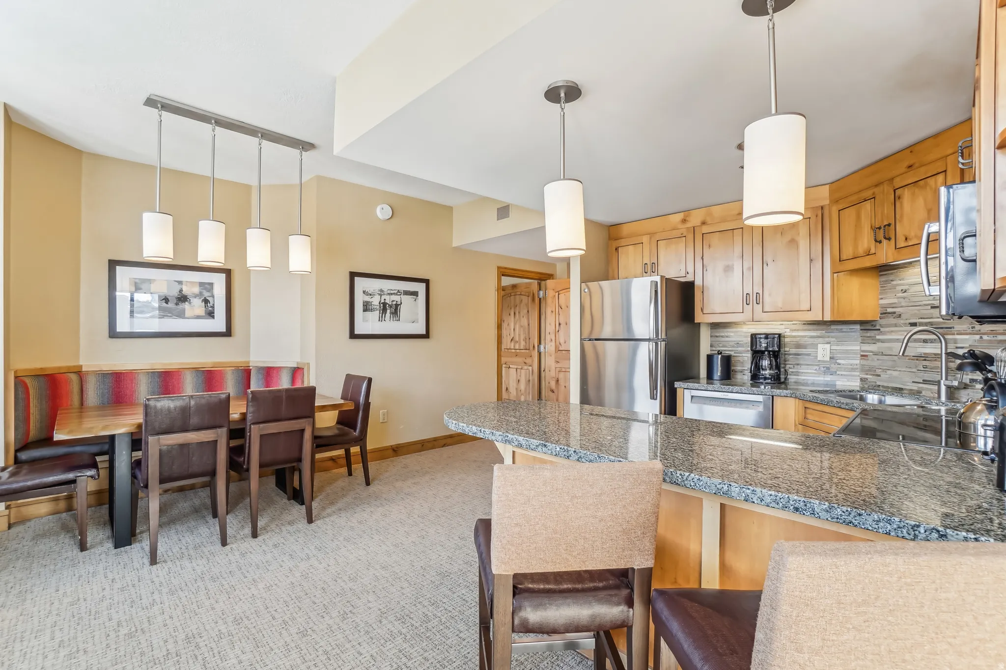Kitchen featuring track lighting, a peninsula, a kitchen breakfast bar, stainless steel appliances, and tasteful backsplash