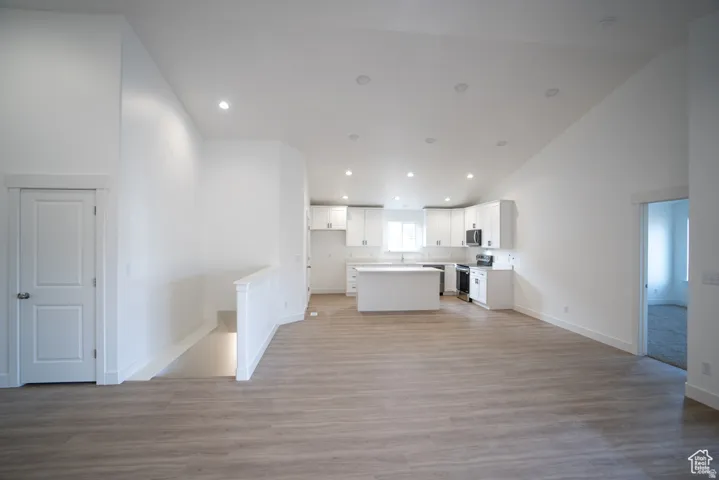 Kitchen featuring open floor plan, white cabinets, a kitchen island, recessed lighting, and stainless steel appliances