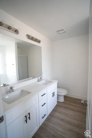 Bathroom with a shower stall, double vanity, dark wood finished floors, and a textured ceiling