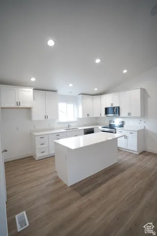 Kitchen featuring a center island, light wood-style floors, white cabinetry, stainless steel appliances, and recessed lighting