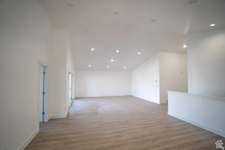 Unfurnished room with light wood-style flooring, recessed lighting, and lofted ceiling