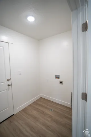 Laundry area featuring wood finished floors, washer hookup, and a textured ceiling