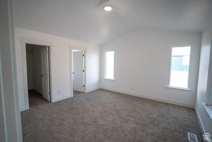 Unfurnished bedroom with a spacious closet and carpet