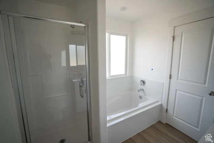Bathroom featuring a stall shower, a bath, and wood finished floors