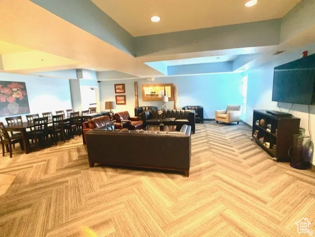 Carpeted living area with a raised ceiling and recessed lighting
