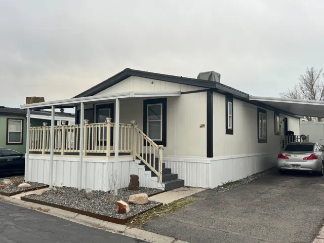 Manufactured / mobile home featuring an attached carport, covered porch, and driveway