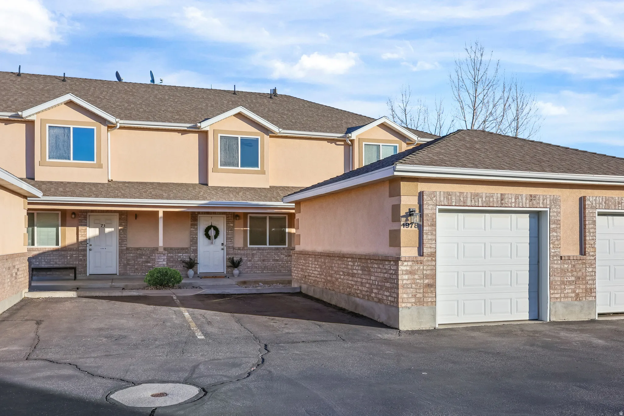 View of front of property featuring brick siding, covered porch, stucco siding, and roof with shingles